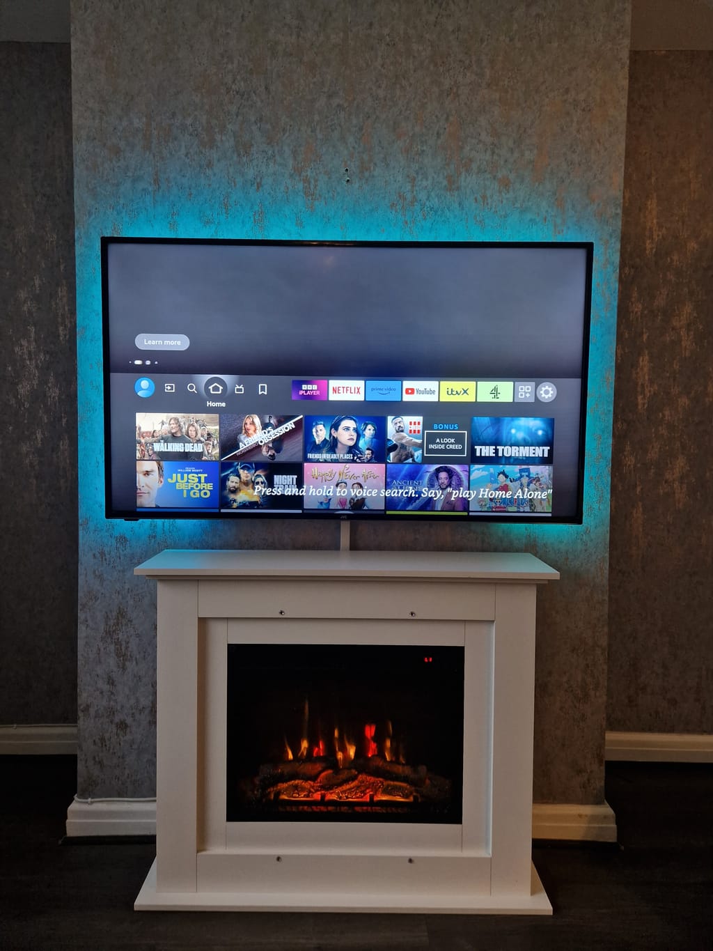 TV above white electric fireplace with LED lighting